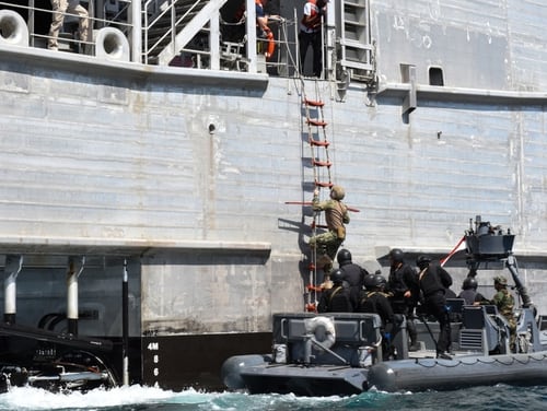 A U.S. Coast Guardsman climbs aboard the expeditionary fast transport Carson City during Exercise Bright Star in September 2018. That same month, a Navy chief allegedly let her sailors get underway on the ship without magazines for their service weapons, according to charge sheets. (Navy)