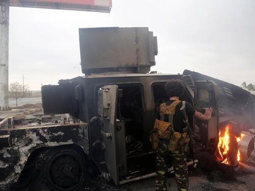 A Houthi rebel inspects a burned armored vehicle on Sept. 13, 2018, reportedly destroyed in an airstrike during clashes between fighters loyal to Saudi-backed exiled President Abd Rabbo Mansour Hadi and Houthi rebels near the eastern entrance of the Yemeni city of Hodeida, as coalition forces seized rebel supply routes into the coastal city. (AFP via Getty Images)