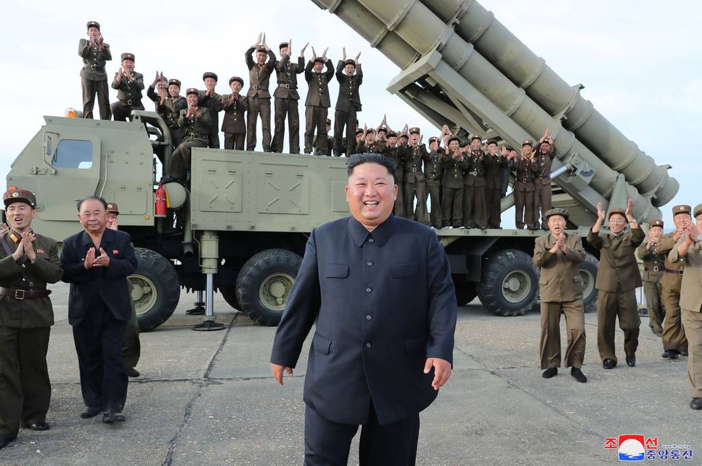 This Aug. 24, 2019, photo provided Aug. 25, shows North Korean leader Kim Jong Un, center, smiling after the test firing of an unspecified missile at an undisclosed location in North Korea.