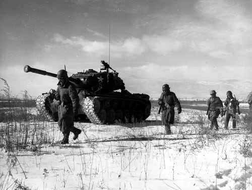 A column of troops and armor of the 1st Marine Division move through communist Chinese lines during their successful breakout from the Chosin Reservoir in North Korea. (Marine Corps)