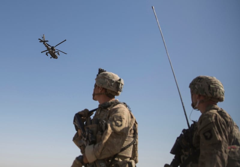 This June 10, 2017, file photo shows an AH-64 Apache attack helicopter providing security from above while CH-47 Chinooks drop off supplies to U.S. soldiers with Task Force Iron at Bost Airfield, Afghanistan. (U.S. Marine Corps Sgt. Justin T. Updegraff/Operation Resolute Support via AP)