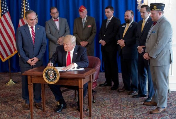 President Donald Trump signs the Veteran's Affairs Choice and Quality Employment Act of 2017 at Trump National Golf Club in Bedminister, N.J., on Aug. 12, 2017. Watching is Veterans Affairs Secretary David Shulkin, left, and standing behind Trump are military veterans. The event was one more more than a dozen in 2017 where Trump heaped public praise on the VA secretary. (Pablo Martinez Monsivais/AP)