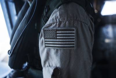 A Marine brandishes a coyote American flag patch on his uniform during a flight around Oahu, Hawaii, Sept. 23, 2014.