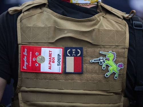 A member of the far-right militia Boogaloo Bois walks next to protestors demonstrating in Charlotte, North Carolina, on May 29, 2020. Affiliated ervice members and veterans have been recently arrested in connection with violent plots against protestors and law enforcement. (Logan Cyrus/AFP via Getty Images)