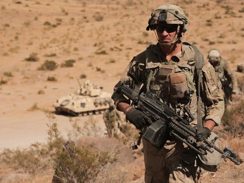 Soldiers assigned to 2nd Brigade Combat Team, 1st Armored Division, scale a hill during a rotation at the National Training Center at Fort Irwin, Calif., in August. The Army wants to extend basic training and revamp its physical fitness program in preparation for high-intensity, near-peer combat. (Spc. Dana Clarke/Army)
