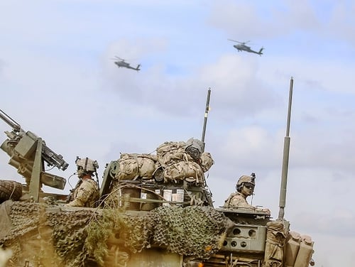 An armored vehicle and AH-64 Apache helicopters secure an area during an exercise at Bemowo Piskie Training Area, Poland, on June 15. (Spc. Hubert D. Delany III/Army)