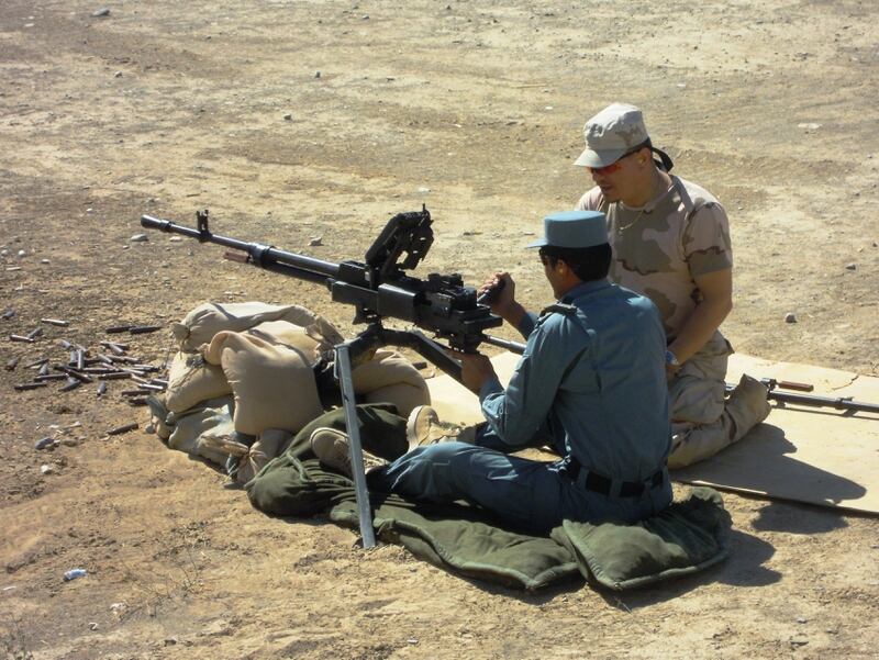 A Romanian military instructor, right, shows an Afghan Uniform Police officer how to use the Russian-made NSV 12.7 millimeter machine gun at the Spin Boldak ANP Training Center in October 2011, at Spin Boldak, Afghanistan. (NATO)