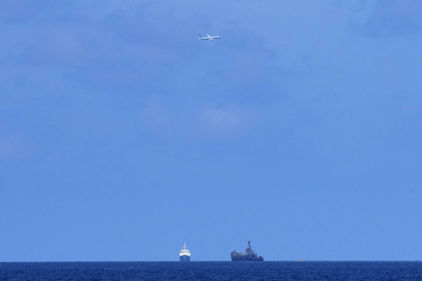 A U.S. Navy plane flies over BRP Sierra Madre, right, and Chinese coast guard ship at the Second Thomas Shoal, locally known as Ayungin Shoal, at the disputed South China Sea on Tuesday, Aug. 22, 2023.