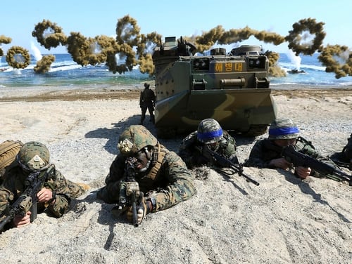 U.S. Marines, left, and South Korean Marines, wearing blue headbands on their helmets, take positions after landing on the beach during a joint military combined amphibious exercise in Pohang, South Korea. (Kim Jun-bum/Yonhap via AP)