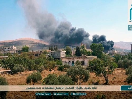 This photo released Tuesday, Sept 4, 2018, by the al-Qaida-affiliated Ibaa News Agency shows smoke rising over buildings that were hit by airstrikes in Mahambal village, in the northern province of Idlib, Syria. The Arabic text reads, 