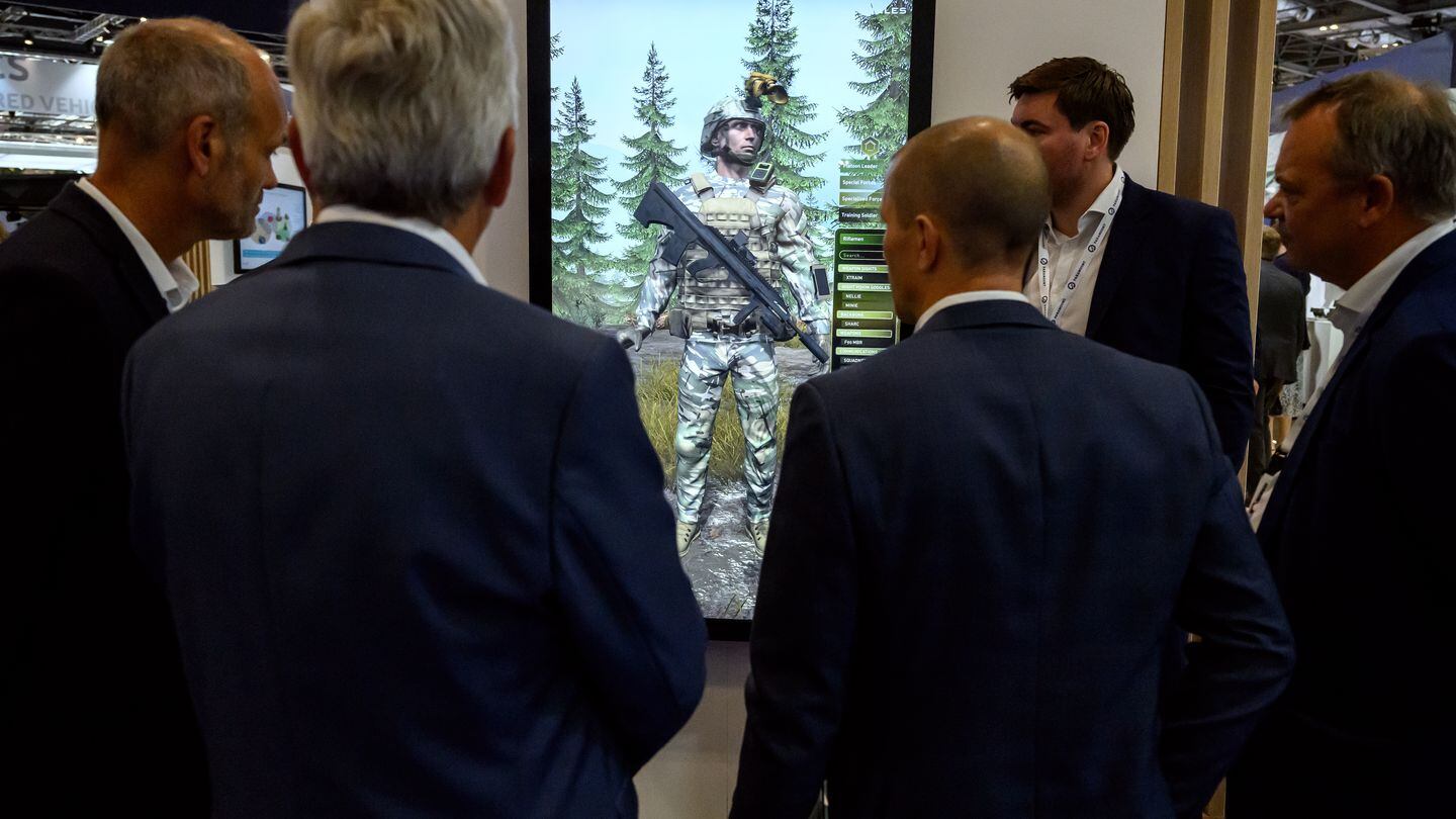 Visitors stand around a display screen as they discuss combat training software on Sept. 12, 2023, at the DSEI event. (Leon Neal/Getty Images)