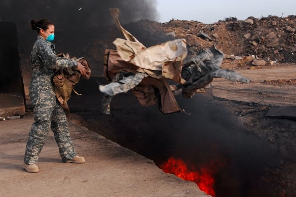 DoD & U.S. Courts do not support enlistees claims : Senior Airman Frances Gavalis, 332nd Expeditionary Logistics Readiness Squadron equipment manager, tosses unserviceable uniform items into a burn pit in Iraq. (Staff Sgt. Julianne Showalter/Air Force)