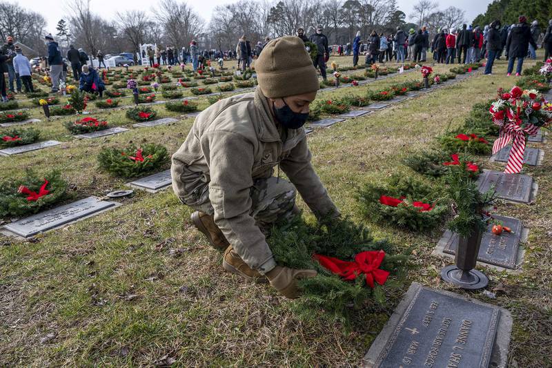 Senior Airman Amber Barkley lays a wreath on a grave at the Delaware Veterans Memorial Cemetery in Millsboro, Del., Dec. 19, 2020.