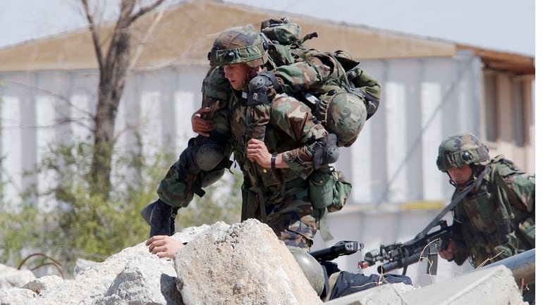 A Marine carries a wounded comrade to safety during an urban combat training demonstration being conducted at the Southern California Logistics Airport, formerly George Air Force Base, during the joint service experimentation process dubbed Millennium Challenge 2002. While the base was closed, the military continued to use it for training exercises. (RDO).