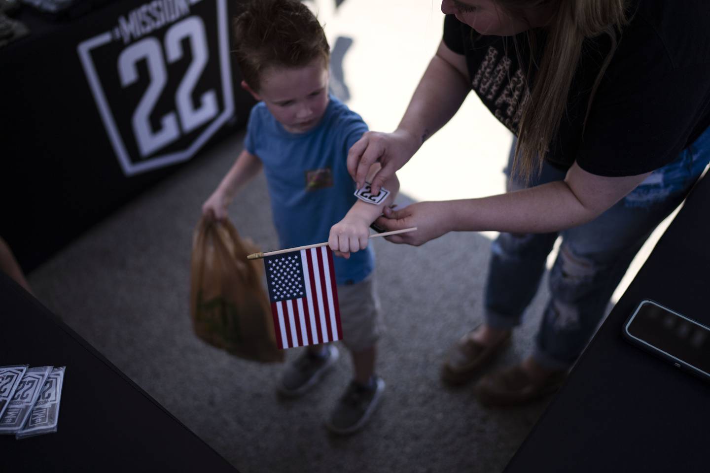 A child gets sticker from Mission 22, a nonprofit that is focused on ending military and veteran suicide, Saturday, June 10, 2023, at a festival in Jacksonville, Texas.