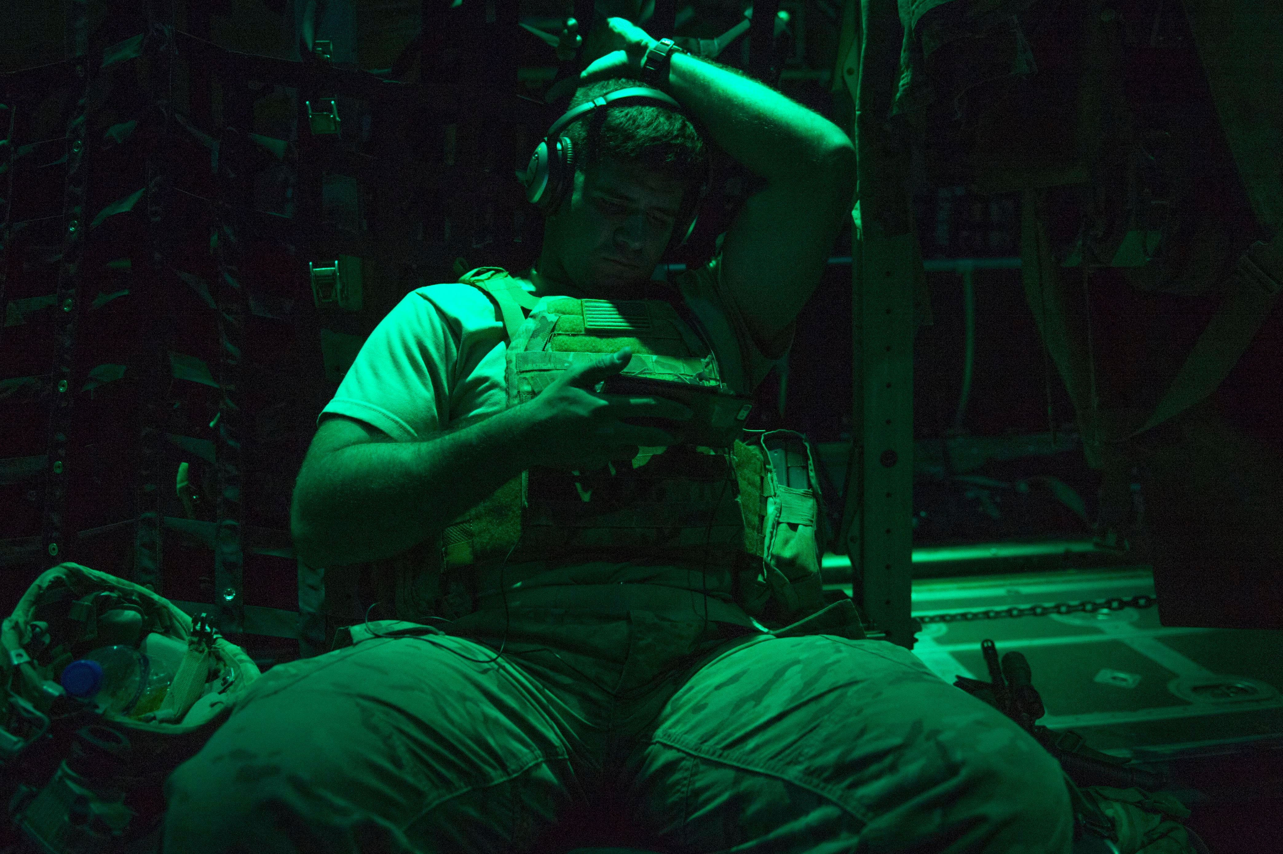 A soldier watches a movie on a personal electronic device on board a U.S. Air Force C-130J Hercules during an air drop in Africa, Dec. 23, 2016. (Tech. Sgt. Joshua J. Garcia/Air Force)
