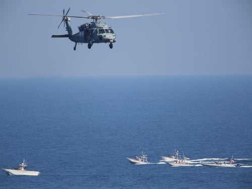 In this Dec. 21, 2018, file photo, a U.S. MH-60 Seahawk helicopter flies over Iranian Revolutionary Guard patrol boats in the Strait of Hormuz. (Jon Gambrell/AP)