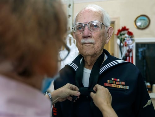 Joseph Hall, 96, of Dunedin, right, holds still as seamstress Susan Williams, 57, of Tarpon Springs, ties a knot into a tie Feb. 3, 2021, in Dunedin, Fla. (Chris Urso/Tampa Bay Times via AP)