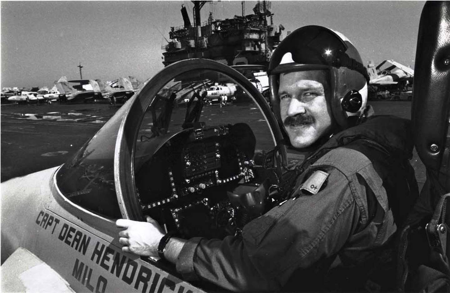 Mark Fox poses in a Hornet with the USS Saratoga in the background a few days after his battle with an Iraqi MiG.
