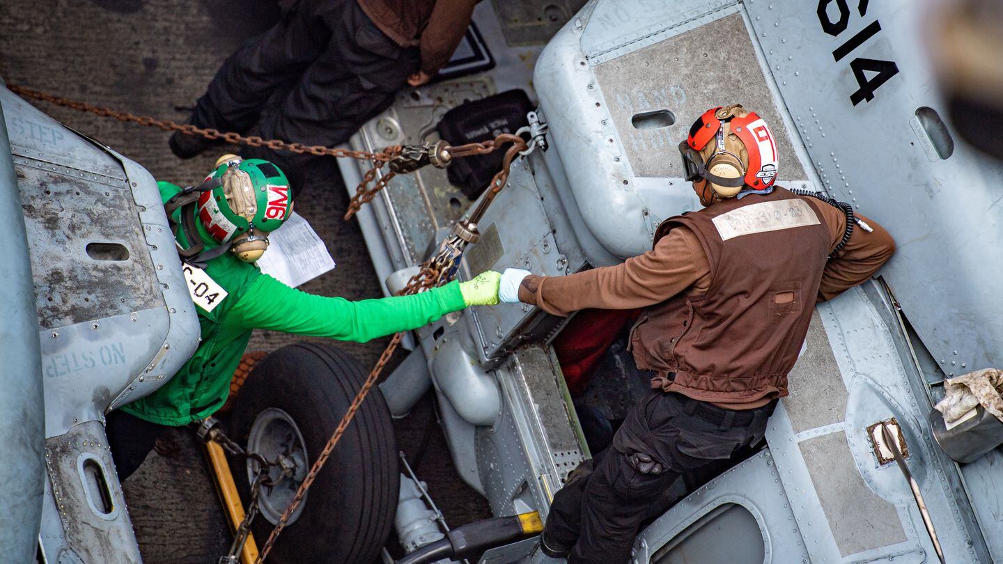 Sailors fist bump while performing maintenance on an MH-60S Sea Hawk from Helicopter Sea Combat Squadron 6 aboard the aircraft carrier Nimitz in February. (MC3 Hannah Kantner/Navy)
