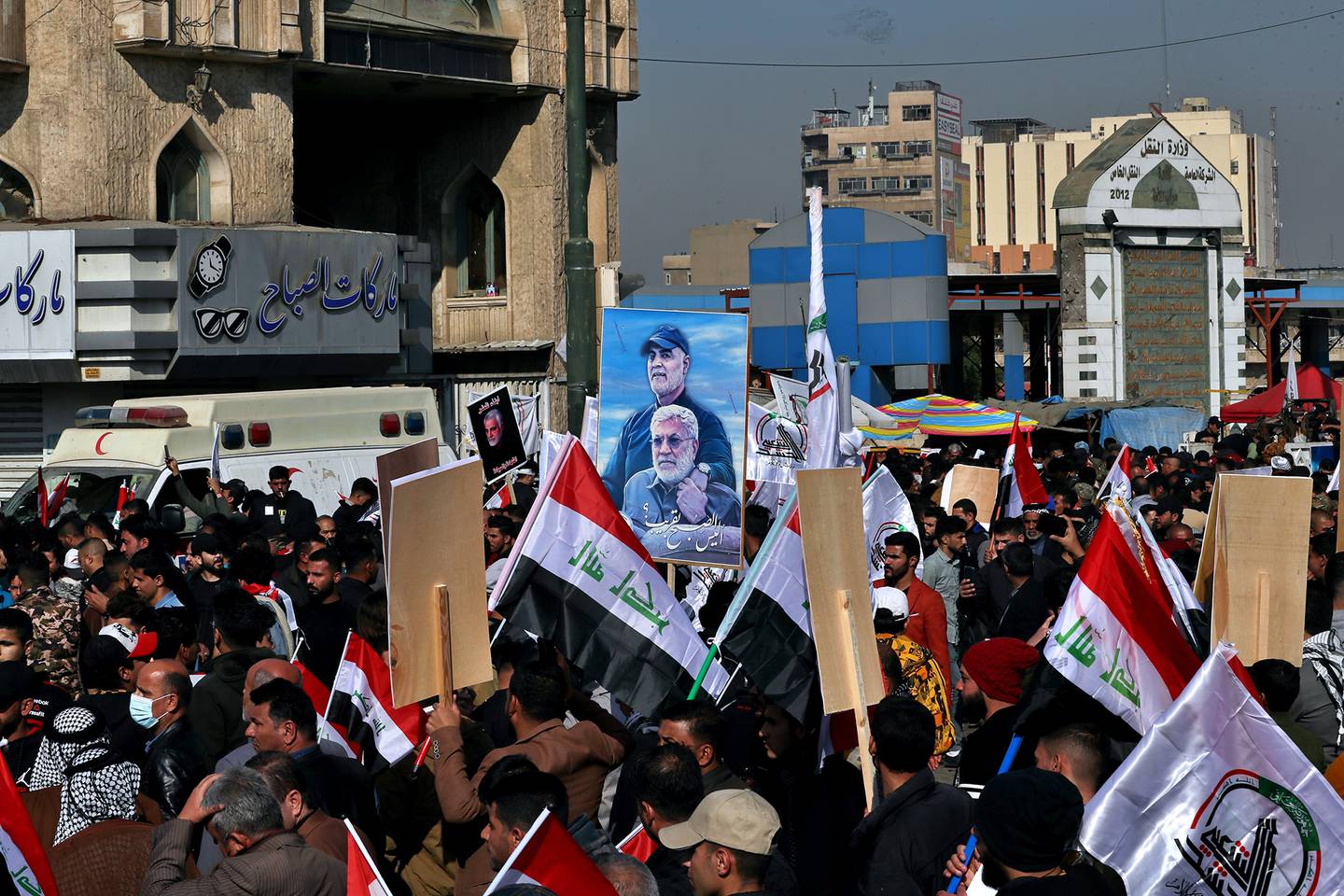 Supporters of the Popular Mobilization Forces hold a poster of Abu Mahdi al-Muhandis, deputy commander of the Popular Mobilization Forces, front, and Gen. Qassem Soleimani, head of Iran's Quds force during a protest, in Tahrir Square, Iraq, Sunday, Jan. 3, 2021.
