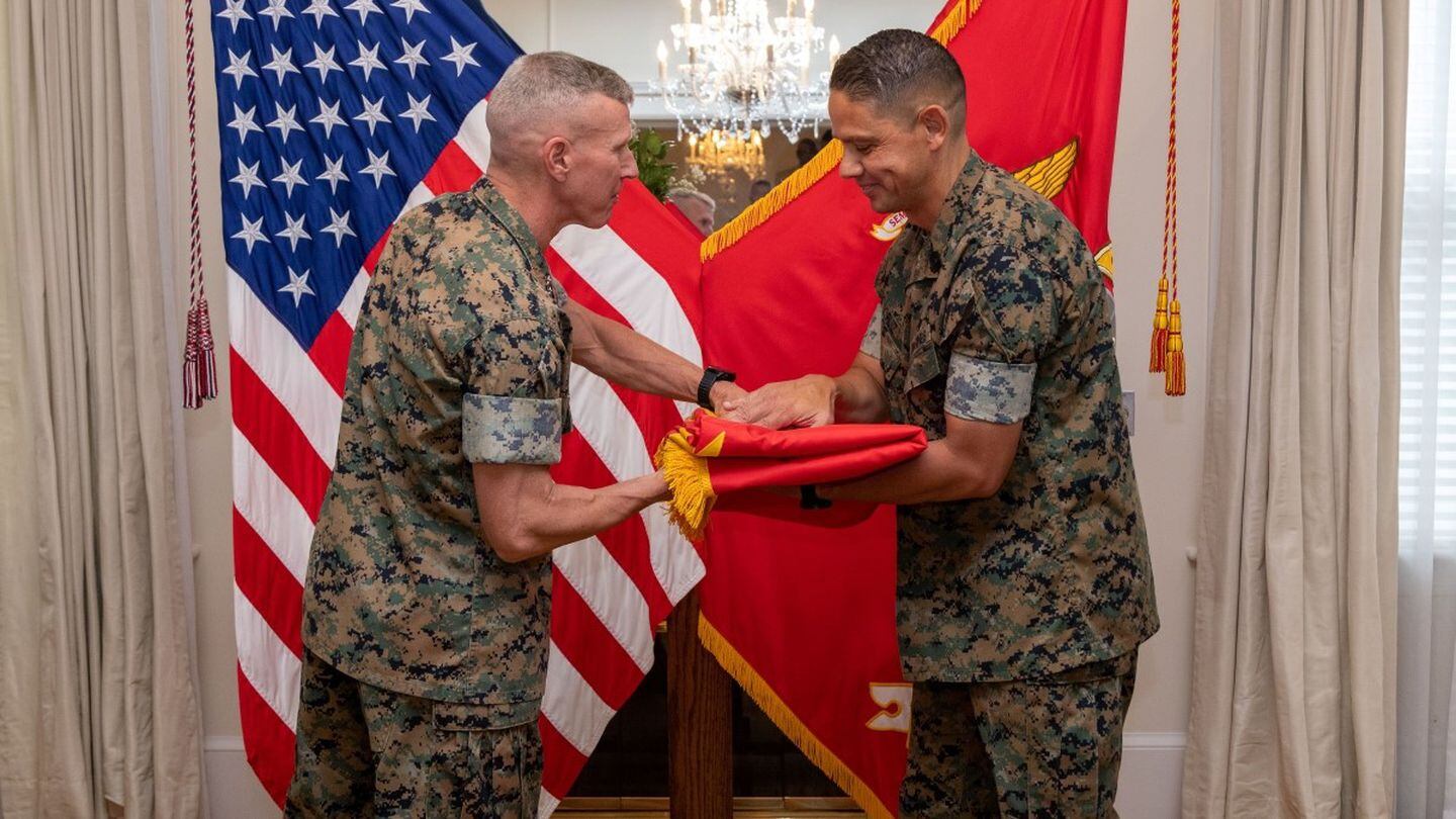 Gen. Eric Smith hands a Marine Corps flag to Sgt. Maj. Carlos Ruiz as part of Ruiz’s promotion to sergeant major of the Marine Corps, as both leaders wear woodland cammies, at Marine Barracks Washington, Aug. 10. (Sgt. Rachaelanne Woodward/Marine Corps)