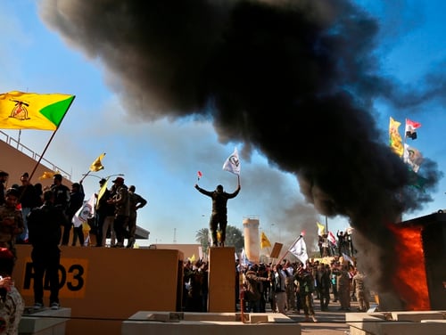 In this Dec 31, 2019, file photo, protesters burn property in front of the U.S. embassy compound, in Baghdad, Iraq. (Khalid Mohammed/AP)