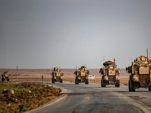 U.S. military vehicles drive on a road in the town of Tal Tamr on Oct. 20, 2019, after pulling out of their base. (Delil Souldeiman/AFP via Getty Images)