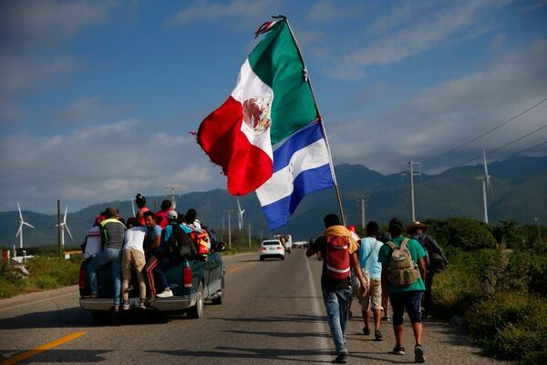 A migrant carrying the flags of Mexico and Honduras walks along the highway as a thousands-strong caravan of Central Americans hoping to reach the U.S. border moves onward from Juchitan, Oaxaca state, Mexico on Thursday. Thousands of migrants resumed their slow trek through southern Mexico on Thursday, after attempts to obtain bus transport to Mexico City failed. (Rebecca Blackwell/AP)