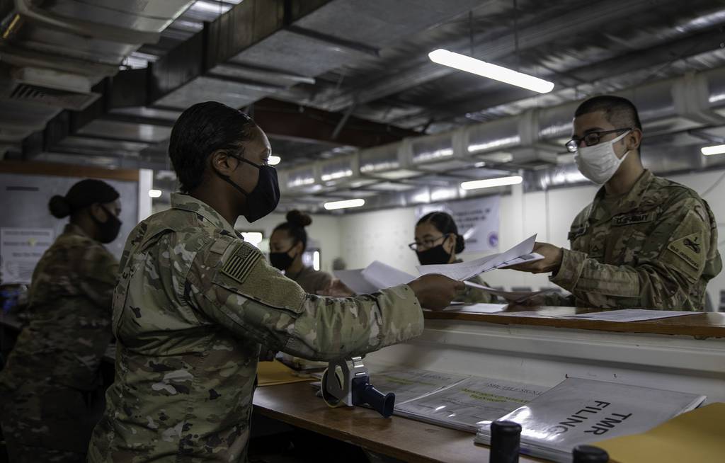 Army 2nd Lt. Daii Gardner and Spc. Natasha Washington hand out voting ballots to soldiers at the Theater Gateway, Camp Arifjan, Kuwait, Oct. 21, 2020.