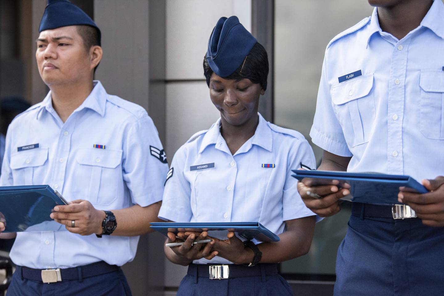 Airman 1st Class Joshua Fancisco, from the Philippines, left, Airman 1st Class D'elbrah Assamoi, from Cote D'Ivoire, center, and Airman 1st Class Jordan Flash, from Jamaica, looks at their U.S. Certificate of Citizenship after signing it following the Basic Military Training Coin Ceremony on April 26, 2023, at Joint Base San Antonio-Lackland, Texas.