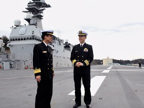 Rear Admiral Hiroshi Egawa, Commander, Escort Flotilla 1, left, and Japanese Maritime Self Defense Forces deputy director of plans and programs, Capt. Toshiyuki Hirata, stand on the JS Izumo's flight deck in port at Naval Base Yokosuka in December. Japan is planning to convert the Izumo into an aircraft carrier and outfit it with F-35s in response to China's rapid military expansion. (Tara Copp/Military Times)