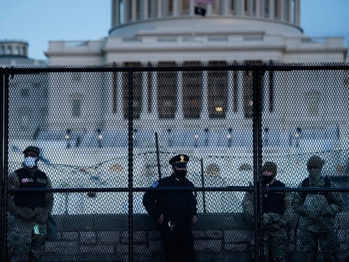 A Capitol Police officer stands with members of the National Guard behind a crowd control fence surrounding Capitol Hill a day after a pro-Trump mob broke into the U.S. Capitol on Jan. 7, 2021, in Washington. (Brendan Smialowski/AFP via Getty Images)