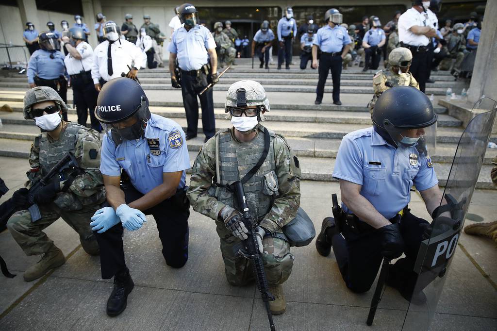 In this June 1, 2020, file photo, Philadelphia police and Pennsylvania National Guard take a knee at the suggestion of Philadelphia Police Deputy Commissioner Melvin Singleton, unseen, outside Philadelphia Police headquarters in Philadelphia, during a march calling for justice over the death of George Floyd.
