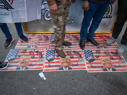 Mourners step over U.S. flags with pictures of President Donald Trump while waiting for the funeral of Iran's top general Qassem Soleimani and Abu Mahdi al-Muhandis, deputy commander of Iran-backed militias in Iraq known as the Popular Mobilization Forces, in Baghdad on Saturday. Thousands of mourners chanting 