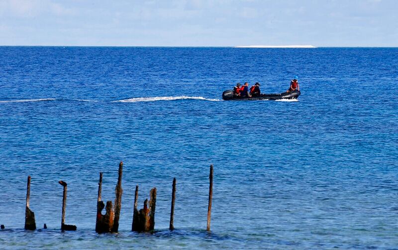 In this 2017 photo, engineers from NAMRIA, the central mapping agency of the Philippine Government, survey the area around the Philippine-claimed Thitu Island with a sandbar sitting on the horizon off the disputed South China Sea in western Philippines. Ships from the Chinese navy and coast guard along with fishing boats from its maritime militia have been deployed to keep watch on Philippine development work on the island of Thitu. (Bullit Marquez/AP)
