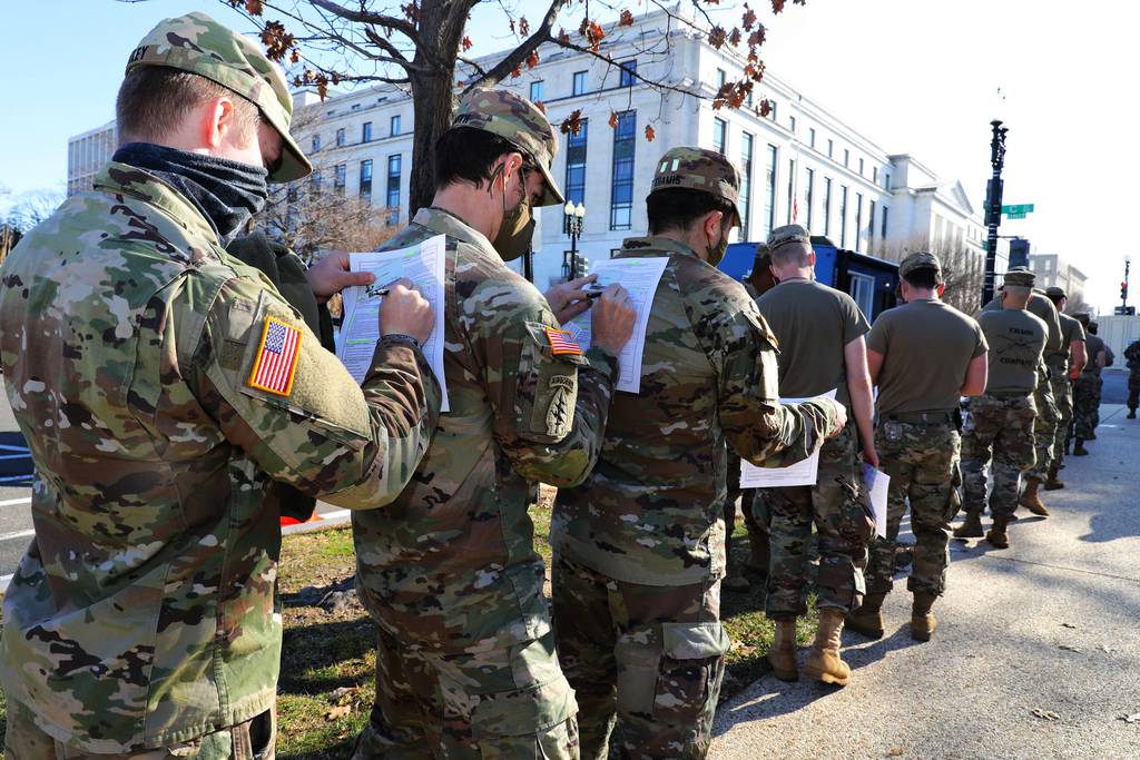 Soldiers in the Maryland Army National Guard use the back of the soldiers in front of them to fill out their medical paperwork to receive the COVID-19 vaccine at the U.S. Capitol Complex in Washington on Jan. 14, 2021.