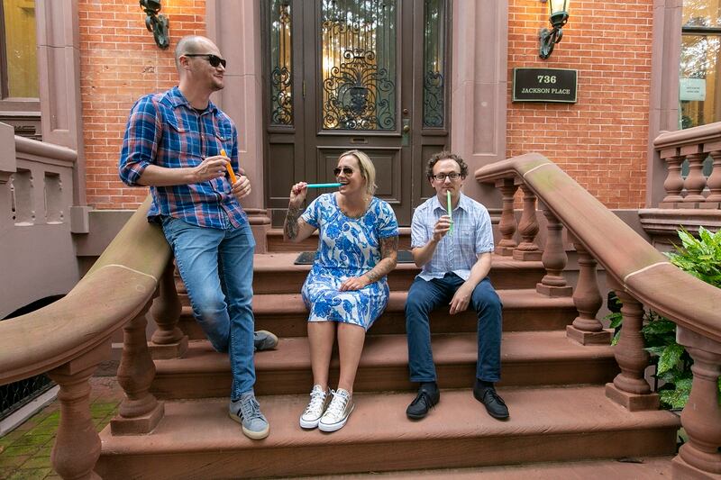 Scott Haselton, digital service expert (at left), Shannon Sartin, executive director of digital services for the Department of Health and Human Services (center), and Sam Gensburg, digital service expert (right), take a break to enjoy freeze pops on the front steps to the U.S. Digital Service. (Alan Lessig/Staff)
