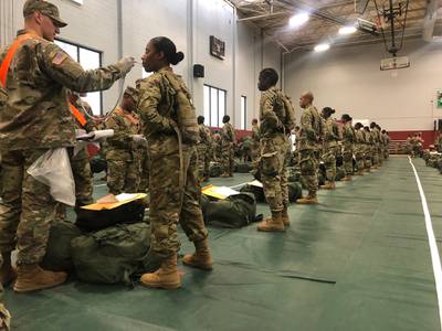 Recent Army basic combat training graduates have their temperatures taken as they arrive at Fort Lee, Va., on March 31, 2020, after being transported using sterilized buses from Fort Jackson, S.C.