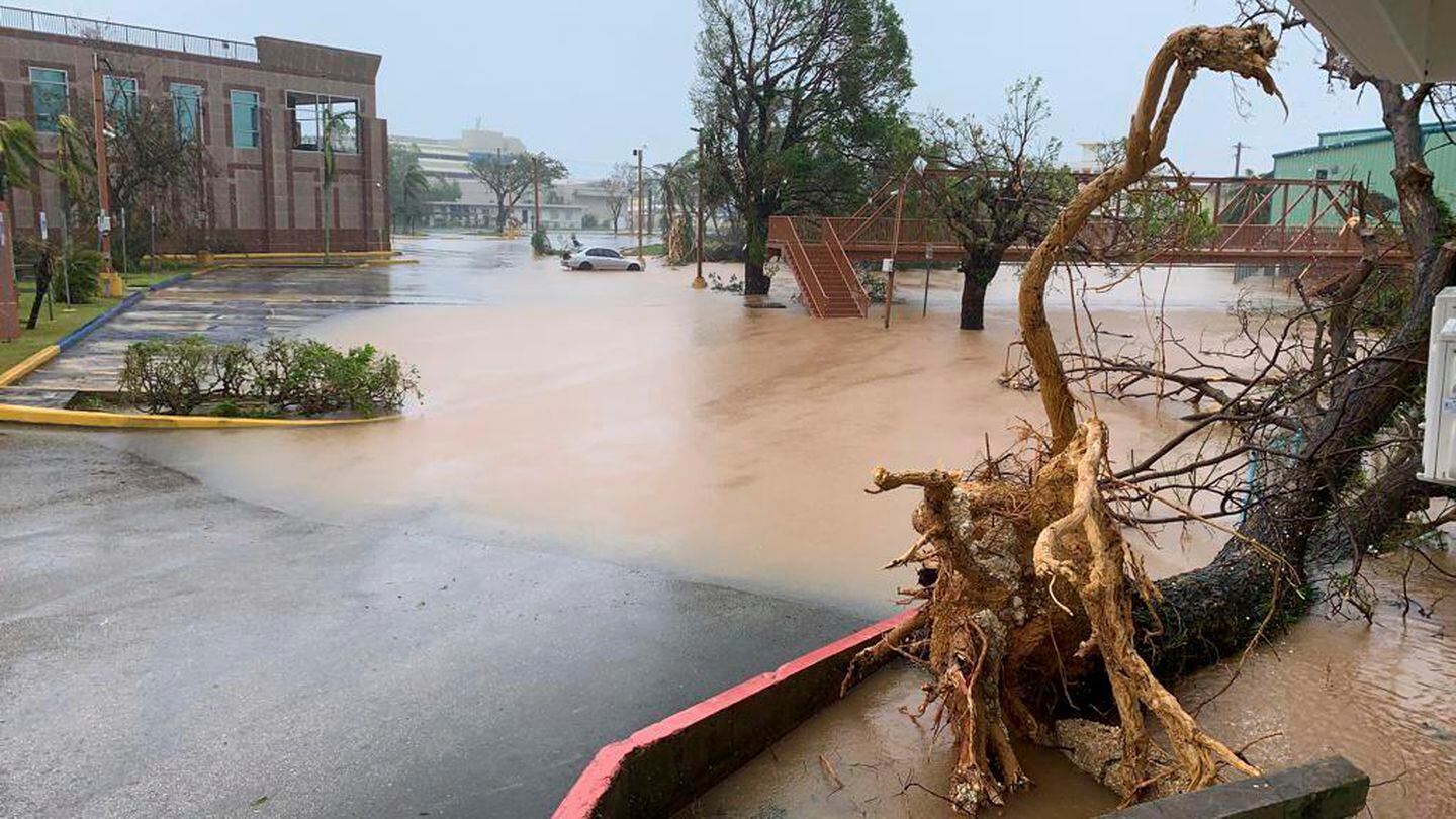 The Hagatna River overflows it's banks and encroaches into the Bank of Guam parking lot in Hagatna, Guam, Thursday. The Category 4 typhoon pummeled the U.S. Pacific territory with howling winds, torrential rain and a life-threatening storm surge as residents hunkered down. (Rick Cruz/The Pacific Daily via AP)