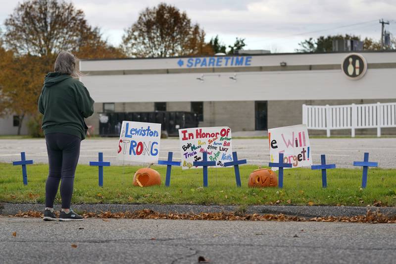 A woman visits a makeshift memorial outside Sparetime Bowling Alley, the site of one of this week's mass shootings, Saturday, Oct. 28, 2023, in Lewiston, Maine.