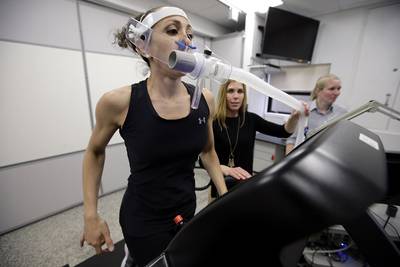 In this April 23, 2019, photo, research scientist Leila Walker, left, is assisted by nutritional physiologist Holly McClung, center, as they demonstrate equipment designed to evaluate fitness levels in female soldiers, not shown, who have joined elite fighting units such the Navy Seals, at the U.S. Army Research Institute of Environmental Medicine, at the U.S. Army Combat Capabilities Development Command Soldier Center, in Natick, Mass.