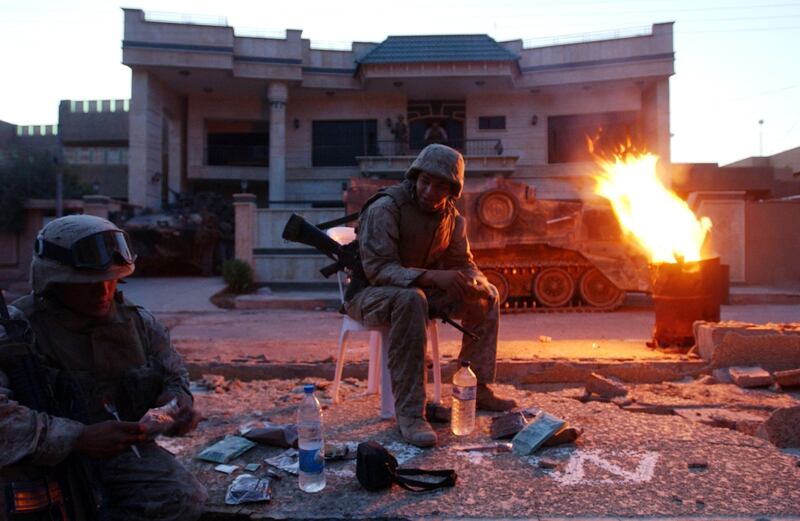 U.S Marines from Bravo Company, 1st Battalion, 3rd Marine Regiment, sit in the street they are patrolling during an offensive November 11, 2004, in Fallujah, Iraq. (Marco Di Lauro/Getty Images)