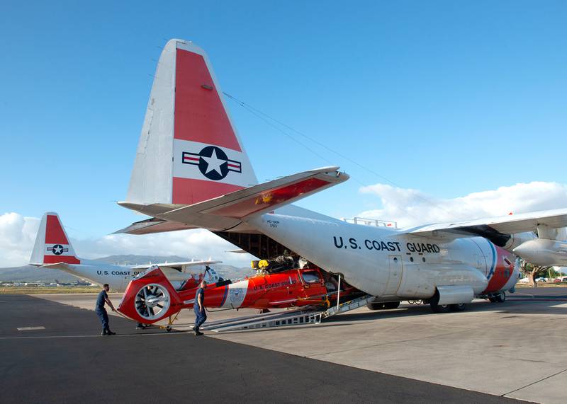 A Coast Guard Air Station Barbers Point aircrew unloads a MH-65E Dolphin helicopter from a HC-130 Hercules airplane on Oahu, Hawaii, Jan. 28, 2021.