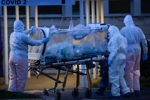 A patient in a bio-containment unit is carried on a stretcher at the Columbus Covid 2 Hospital in Rome on Monday. Italian health authorities are toiling to contain the pandemic. At least three U.S. Navy cases have been tied to Italy. (Alessandra Tarantino/AP)