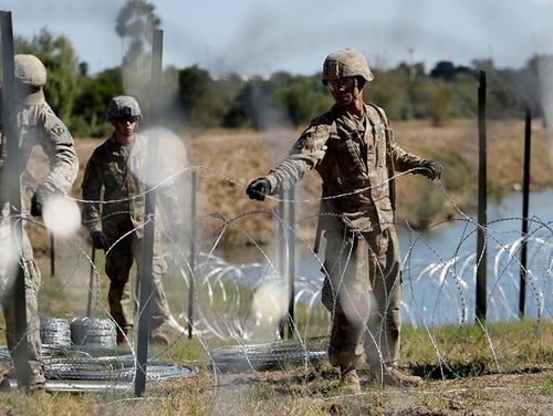 Troops install multiple tiers of concertina wire along the banks of the Rio Grande near the Juarez-Lincoln Bridge at the U.S.-Mexico border in Laredo, Texas. The Pentagon announced Thursday it would decrease its contribution of forces from 5,500 to 4,000. (Eric Gay/AP)