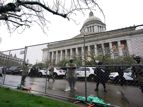 Members of the Washington National Guard stand near a fence surrounding the Capitol in anticipation of protests Monday, Jan. 11, 2021, in Olympia, Wash. (Ted S. Warren/AP)