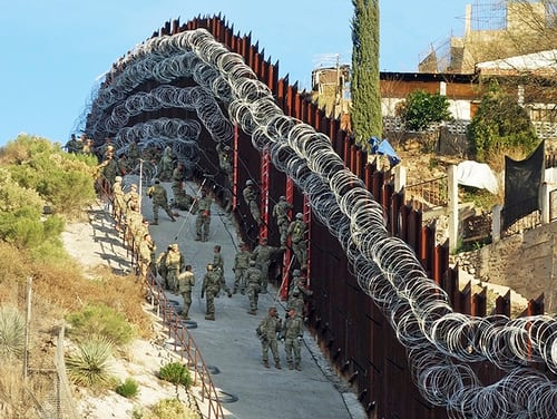 Soldiers place additional concertina wire to the border fence on a hillside above Nelson Street in downtown Nogales, Ariz. (Jonathan Clark/Nogales International via AP)