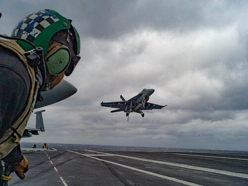 Flight deck crewmen watch the approach of aircraft during the carrier's Composite Unit Training Exercise (Mark D. Faram/Staff)