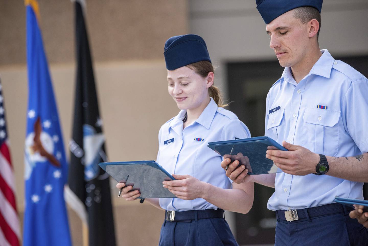 Airman 1st Class Natalia Laziuk, from Russia, left, and Airman 1st Class Ross Mudie, from South Africa, look at their U.S. Certificates of Citizenship after signing it following the Basic Military Training Coin Ceremony on April 26, 2023, at Joint Base San Antonio-Lackland, Texas.